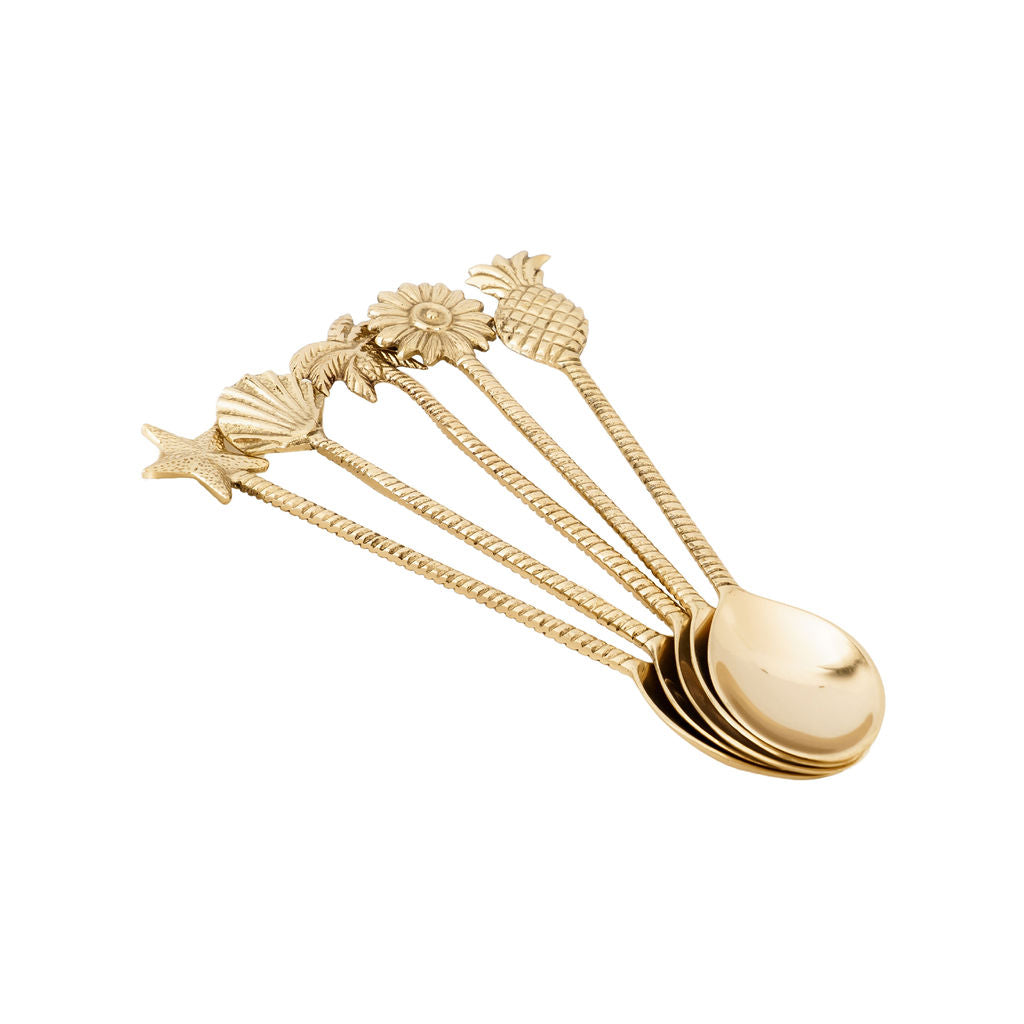 Set of brass spoons with decorative tropical handles on a white background