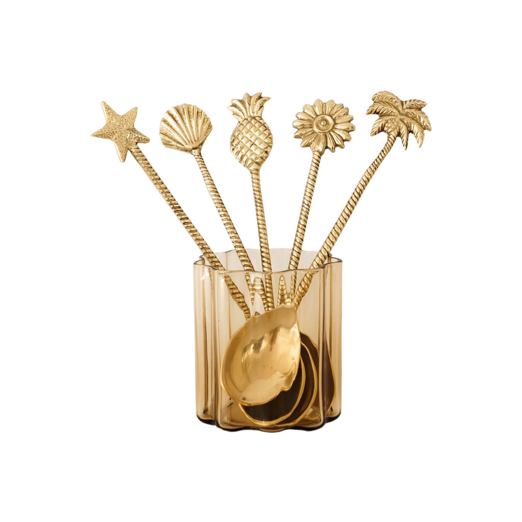 Set of brass spoons with decorative tropical handles on a white background